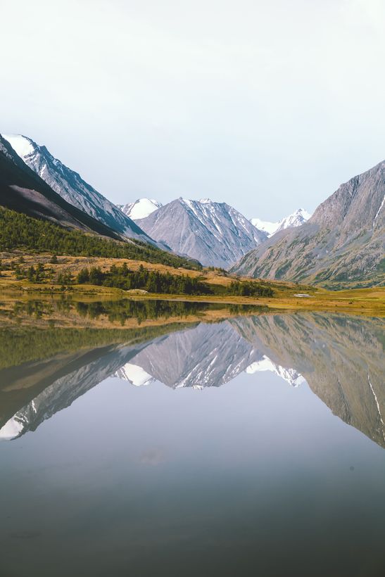 Des montagnes qui se reflètent à la surface parfaitement calme d'un lac